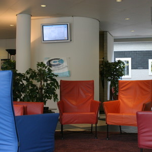 Wachtruimte met stoelen en Info-Kanaal scherm aan de muur