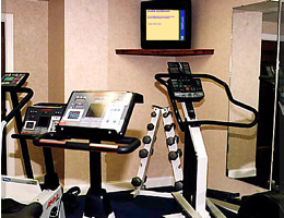 Fitnessruimte met apparatuur en Info-Kanaal scherm aan de muur