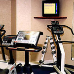 Fitnessruimte met apparatuur en Info-Kanaal scherm aan de muur